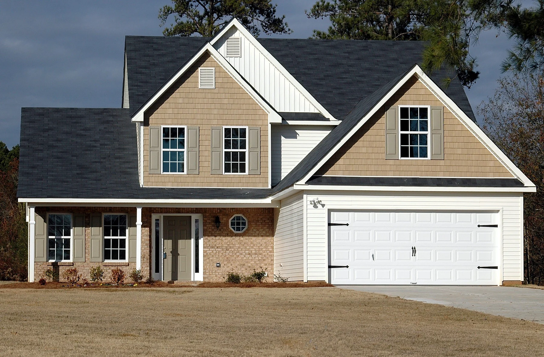 Neutral-sided suburban home with an attached two-car raised-panel garage and a simple lawn